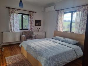 a bedroom with a bed and a chair and windows at Villa in Trilofos-close to the beach in Thessaloniki