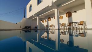 Hotel Madalena في مدينة ميكونوس: مبنى فيه كراسي وانعكاس في الماء