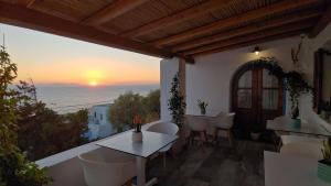 balkon ze stołem, krzesłami i zachodem słońca w obiekcie Hotel Madalena w mieście Mykonos