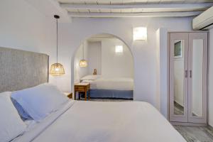 Hotel Madalena في مدينة ميكونوس: غرفة نوم بيضاء بسريرين ومرآة