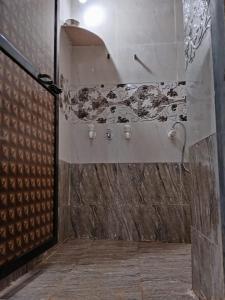 y baño con ducha y pared de piedra. en Om Laxmi Narayan Homestay, en Diveagar