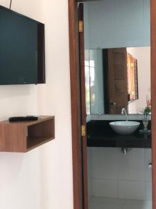 a bathroom with a sink and a mirror at Conchas e Corais Suítes in Marau