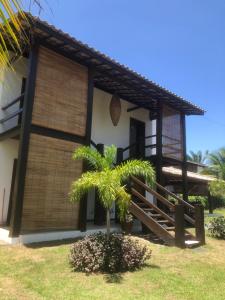 a house with a palm tree in front of it at Conchas e Corais Suítes in Marau