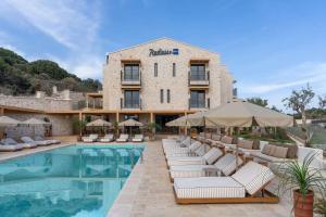a hotel with a pool with lounge chairs and umbrellas at Radisson Blu Hotel, Kas in Kaş