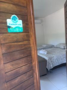 a door with a sign on it next to a bed at Conchas e Corais Suítes in Marau