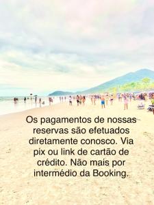 a group of people standing on a beach at Casa d'Aroeira Condomínio Luxo - Centro de Juqueí - 2 quadras do mar - Serviço de Praia - Roupa de Cama 600 fios algodão Egípcio - Toalhas Banho e Praia - Tudo Novo - Estacionamento - Cozinha completa - Consulte unidades com Ofurô Hidro e Cromoterapia in Juquei