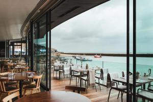 un restaurante con mesas y sillas y vistas al agua en Rocksalt Rooms, en Folkestone