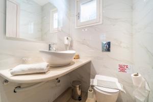 a white bathroom with a sink and a toilet at Lido Sofia Apartments in Agios Gordios