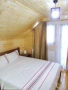 a bedroom with a large white bed and a window at Cabana Dintre Munti in Vidra