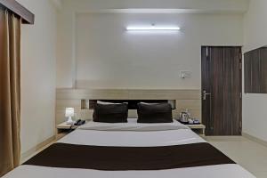 um quarto com uma cama grande e almofadas pretas em OYO Flagship Hotel Madhurima Inn em Lucknow
