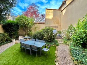 a table and chairs in a garden with grass at L’Hôtel Particulier des Anges in Reims