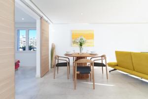 a dining room with a table and chairs and a yellow couch at L'Aiglon By SCLS Locations in Vallauris