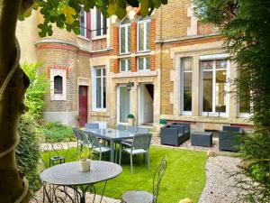 un patio con tavolo e sedie di fronte a un edificio di L’Hôtel Particulier des Anges a Reims