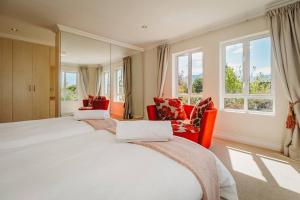 a bedroom with two beds and two chairs and windows at Fifty1 on Long on Kingswood Golf Estate in George