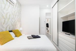 a bedroom with a white bed with yellow pillows and a tv at Chueca San Antón Apartment in Madrid