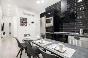 a black and white kitchen with a table and chairs at Chueca San Antón Apartment in Madrid +26 photos