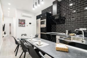 a kitchen with black brick walls and a table and chairs at Chueca San Antón Apartment in Madrid