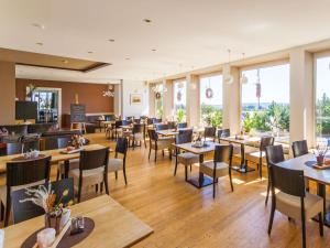 un comedor con mesas, sillas y ventanas en Berghotel Deutscher Flieger Wasserkuppe, en Gersfeld