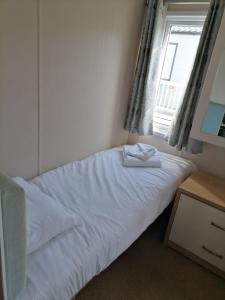 1 dormitorio con 1 cama blanca y ventana en Kent Coast Holiday Park en Rochester