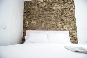 a bedroom with a stone wall and a white bed at Casaimpecablecentro in Tarifa