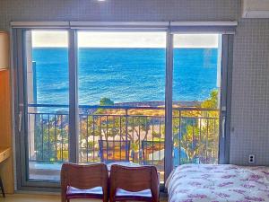 a bedroom with a view of the ocean from a balcony at OROJEJU in Seogwipo
