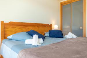 a bedroom with a bed with blue and white pillows at Buarcos Ocean Village in Buarcos