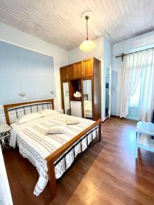 Patras Rooms في فورني إيكارياس: غرفة نوم بسرير كبير وارضية خشبية