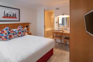 a hotel room with a bed and a desk and a bathroom at Queensway Hotel, Sure Hotel Collection by Best Western in London
