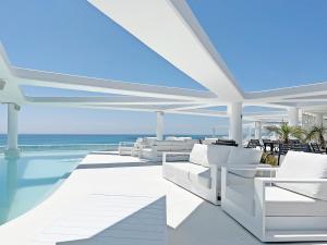 um pátio com cadeiras brancas e uma piscina em Global Properties, Apartamento con terraza y vistas al mar y a la montaña em Canet d'En Berenguer