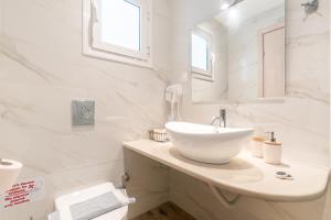 a white bathroom with a sink and a mirror at Lido Sofia Apartments in Agios Gordios