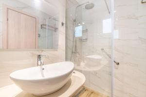 a white bathroom with a sink and a shower at Lido Sofia Apartments in Agios Gordios
