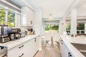 a kitchen with white counters and white cabinets and windows at Upscale 3BR/2.5BATH House +Games room and Yard! in Mississauga