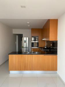 a kitchen with wooden cabinets and a stainless steel refrigerator at NICE DUPLEX, PRAIA in Praia