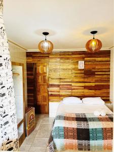 Pousada Maria Bonita Abreu e Lima في Maricota: غرفة نوم بسرير مع جدار خشبي