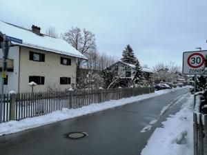 una calle nevada con una valla y una señal de límite de velocidad en Ferienwohnung Borger en Sauerlach
