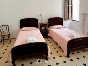 two beds in a room with two chairs and a table at L' Auletta in Cafayate