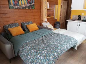 a bedroom with a bed with a green comforter at Gîte du Chalet - Le studio en pleine nature 