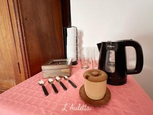 uma mesa coberta com uma toalha de mesa rosa e comodidades para preparar café em L' Auletta em Cafayate
