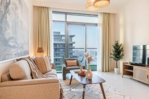 a living room with a couch and a tv at Manzil - 1BR Apartment in Emaar Beachfront with Private Beach & Marina Access in Dubai