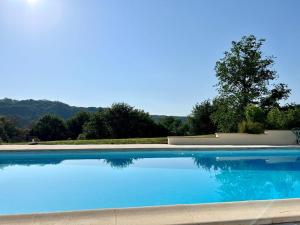 een groot blauw zwembad met een boom op de achtergrond bij Domaine la Cabane luxe vakantiehuizen met zwembad in Dégagnac
