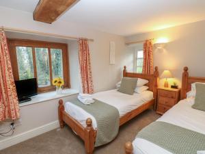 a bedroom with two beds and a tv and a window at The Tithe Barn in Barnard Castle
