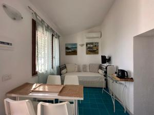 een woonkamer met een bank en een tafel en stoelen bij Domus Clementina Apartment with sea view Villasimius in Simius