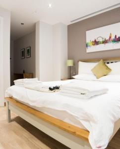 a large white bed with white sheets and pillows at Barbican Serviced Apartments in London