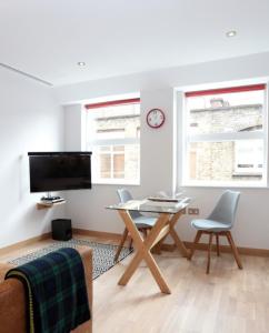 a living room with a table and chairs and a clock at Barbican Serviced Apartments in London