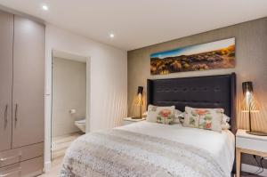 a bedroom with a large bed and a painting on the wall at 107 Dorpstraat Boutique Hotel in Stellenbosch