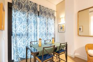 una sala da pranzo con tavolo, sedie e finestra di Angeles Deluxe Suite by Valcambre a Siviglia