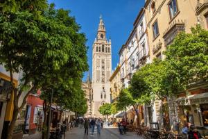 un edificio alto con una torre dell'orologio in lontananza di Angeles Deluxe Suite by Valcambre a Siviglia