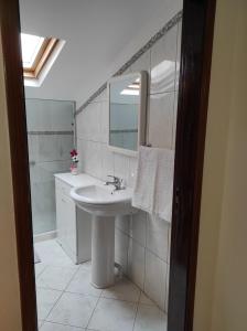 a white bathroom with a sink and a mirror at Casa Câmara in Arco da Calheta