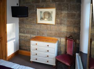 a bedroom with a dresser and a tv on a brick wall at Ashfield House in Pateley Bridge