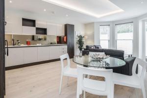 een keuken en een woonkamer met een tafel en stoelen bij Roomspace Serviced Apartments- Lyons House in Surbiton